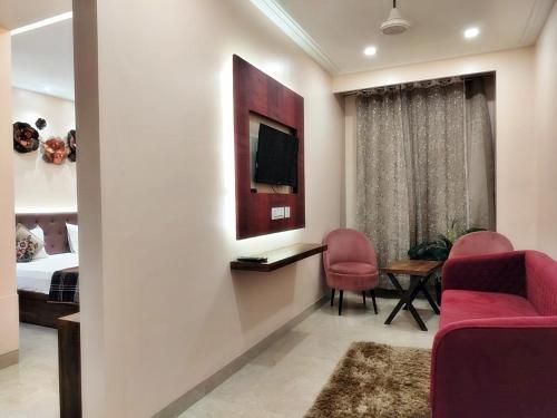 a living room with a tv and a bedroom at Hotel Luxuria in Ludhiana