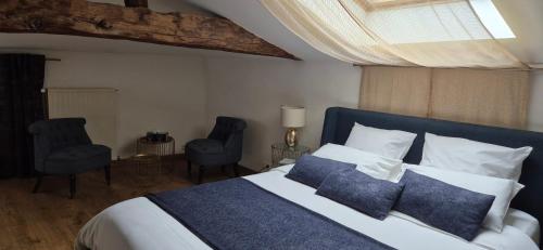 a bedroom with a bed with blue pillows and two chairs at Domaine de la Fée-Licité in Jullié