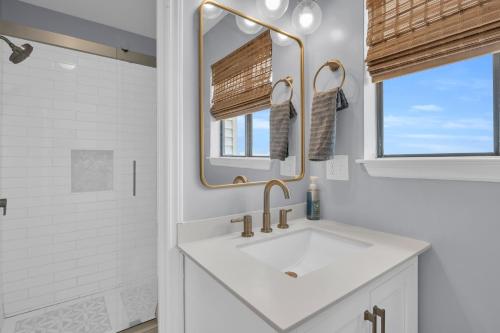 a white bathroom with a sink and a mirror at Tipsy Traveler in North Topsail Beach