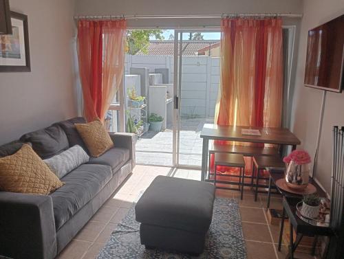 a living room with a couch and a piano at The Sands Ground-floor apartment in Blouberg in Cape Town
