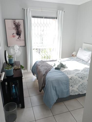 a bedroom with a bed and a window at The Sands Ground-floor apartment in Blouberg in Cape Town