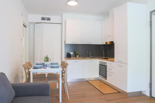 a kitchen with white cabinets and a table with chairs at Spina Verde Palazzo in Cavallasca