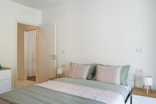 a white bedroom with a large bed with pillows at Spina Verde Palazzo in Cavallasca