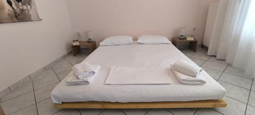 a large bed with white sheets and towels on it at Διαμέρισμα στο Ρίο Πατρών in Rio