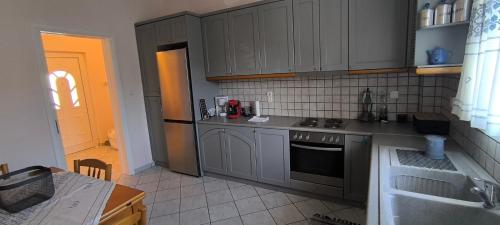a kitchen with gray cabinets and a stove top oven at Διαμέρισμα στο Ρίο Πατρών in Rio