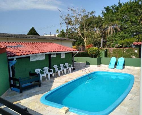 ein großer Swimmingpool mit Stühlen und einem Haus in der Unterkunft Seu lar na Praia, Condomínio Vila Gustavo-excelente localização in Caraguatatuba