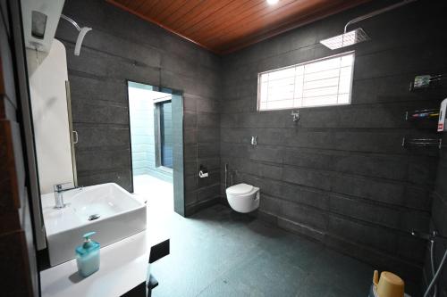 a bathroom with a sink and a toilet and a window at Tinton Adventure Resort in Golikatte