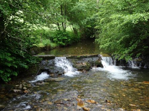 a stream of water with a bridge over it at Du Coté de Lacoume in Anla