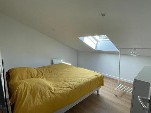a bedroom with a yellow bed with a skylight at Maison au cœur du pays de Rabelais in Lerné