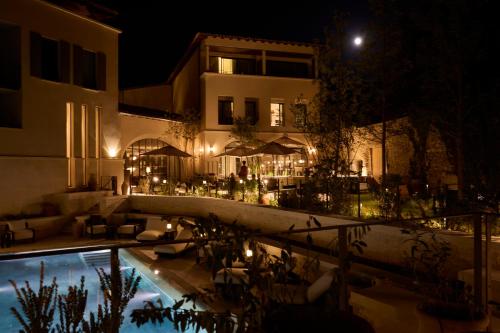 a villa with a swimming pool at night at L'Isle de Leos Hotel & Spa - MGallery Collection in LʼIsle-sur-la-Sorgue