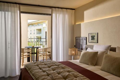 a bedroom with a large bed and a balcony at L'Isle de Leos Hotel & Spa - MGallery Collection in LʼIsle-sur-la-Sorgue