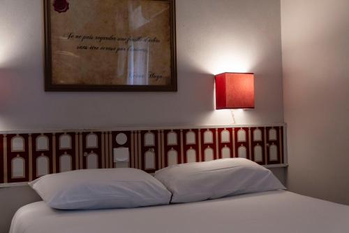 a bedroom with a bed with a red lamp at Hotel Ours Blanc - Victor Hugo in Toulouse