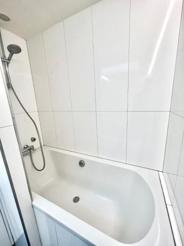 a white bath tub in a white tiled bathroom at Superbe Duplex lumineux aux Coeur d 'Orsay in Orsay