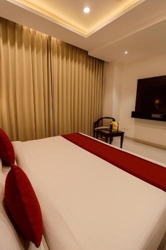 a bedroom with a bed with red pillows and a television at Hotel Lycoris Zirakpur Chandigarh # Ambala Chandigarh Highway Hotel # Ample Parking Space # Lift in Chandīgarh