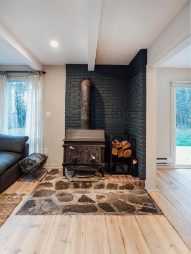 a living room with a brick fireplace with a stove at Catskill MNTN Escape 5 BR 3 bath Villa Hot Tub Fire Pit Best Group Stay in Prattsville