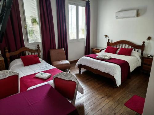 a bedroom with two beds with red and white sheets at Hotel Romi in Colonia del Sacramento