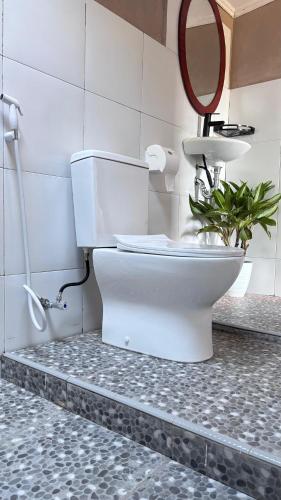 a bathroom with a toilet with a mirror and a plant at Tetebatu flower in Tetebatu