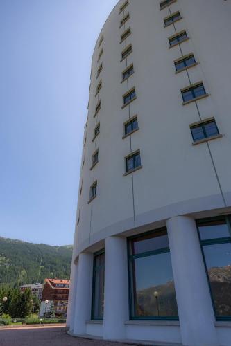 a white building with windows and mountains in the background at Hotel la Torre in Sauze dʼOulx