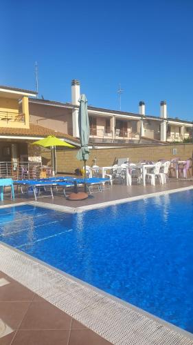 a swimming pool with tables and chairs and an umbrella at TUSCIA RELAx MARE in Civitavecchia