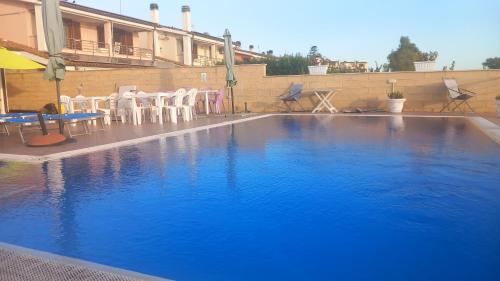 a large blue swimming pool with chairs and tables at TUSCIA RELAx MARE in Civitavecchia