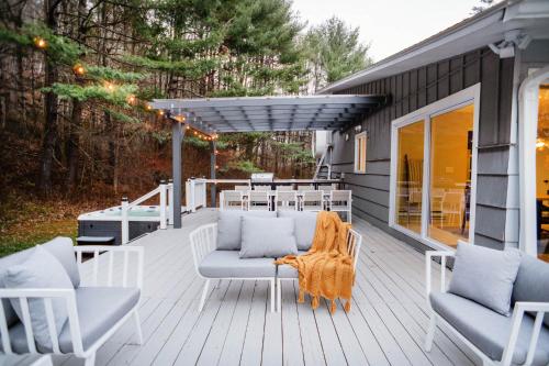 a deck with white furniture and a table and chairs at Catskill MNTN Escape 5 BR 3 bath Villa Hot Tub Fire Pit Best Group Stay in Prattsville