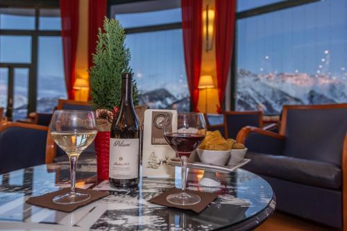 a table with two glasses of wine and cheese at Hotel la Torre in Sauze dʼOulx