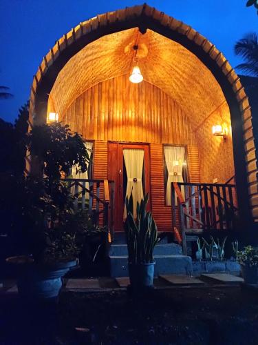 a wooden cabin with an arched entryway at night at Tetebatu flower in Tetebatu