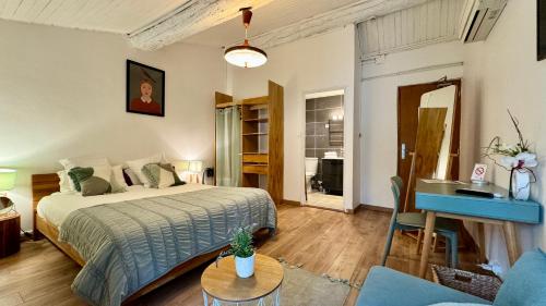 a bedroom with a bed and a desk in a room at Hotel Le Galambre in Nîmes