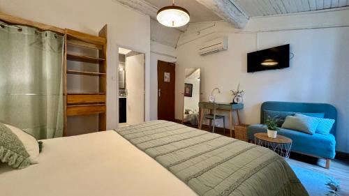 a bedroom with a bed and a blue couch at Hotel Le Galambre in Nîmes
