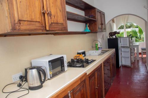 a kitchen with a microwave and a stove top oven at Studio Cecile in Malindi