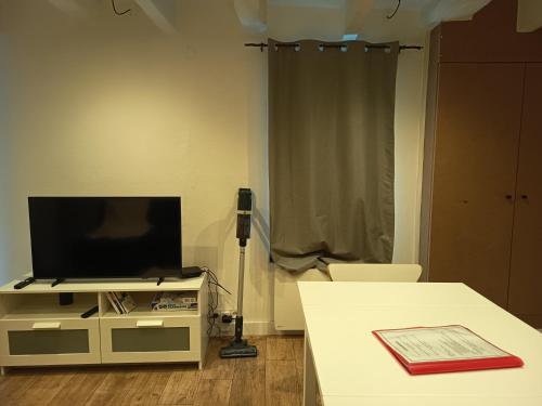 a living room with a tv on a stand with a table at Villeneuve's historic center in Villeneuve-lès-Avignon
