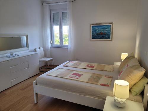 a white bedroom with a bed and a television at Mary in Zadar
