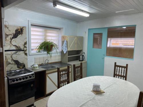a kitchen with a table and a sink and a stove at Hospedaje Corina Coyhaique in Coihaique