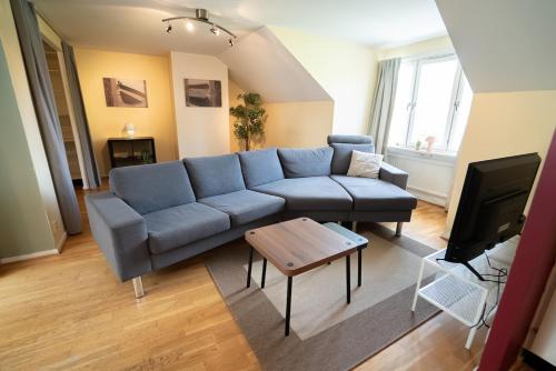 Una sala de estar con un sofá azul y una mesa. en Harbor-View Loft - 2BR Near City, en Gotemburgo
