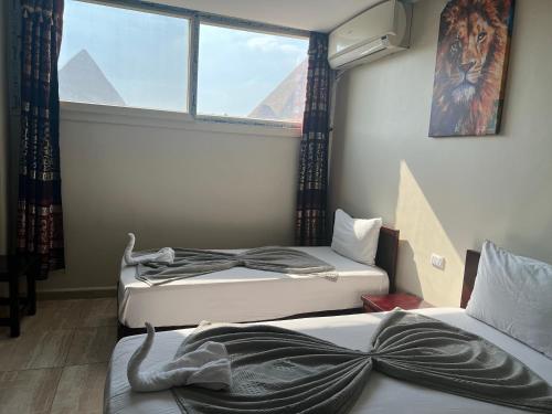 two beds in a room with a window at Comfort Sphinx & Pyramids Inn in Cairo