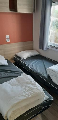 two beds sitting in a room with a window at MOBIL HOME CONFORT PLUS - 40m2 - 3ch - 2 SDB - Camping 4 étoiles - BONNE ANSE 56 in Les Mathes