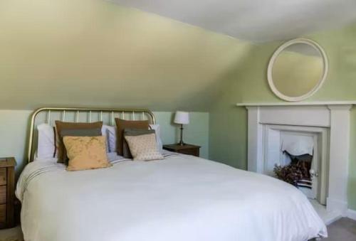 Schlafzimmer mit einem weißen Bett und einem Spiegel an der Wand in der Unterkunft Hope Cottage by the sea in Saint Monance