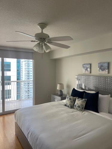 a bedroom with a white bed with a ceiling fan at Lux condo on 25floor in Brickell in Miami