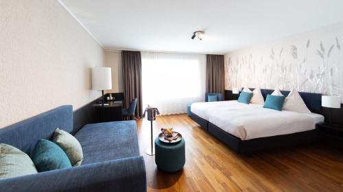 a hotel room with two beds and a couch at HOTEL illuster - Urban & Local in Uster