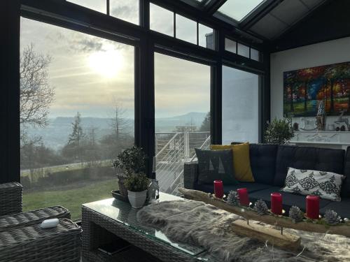 a living room with a couch and a large window at Paradies in der Vulkaneifel - Panorama-Blick und Wintergarten für jedes Wetter in Burgbrohl