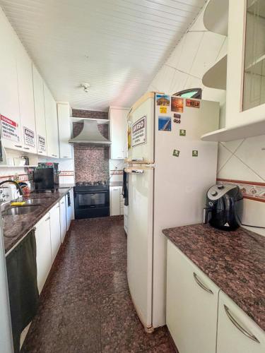 a small kitchen with a white refrigerator and counters at Hostel BH in Belo Horizonte