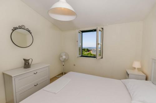 a bedroom with a white bed and a window at Apartments Voga in Maslinica