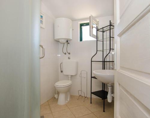 a white bathroom with a toilet and a sink at Apartments Voga in Maslinica