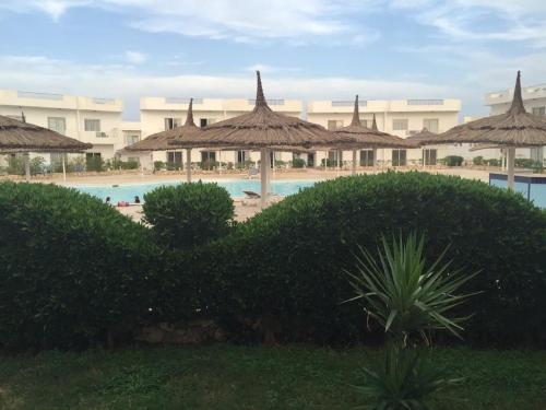 a resort with a swimming pool and straw umbrellas at Luxury Apartment Ritz Carlton in Sharm El Sheikh