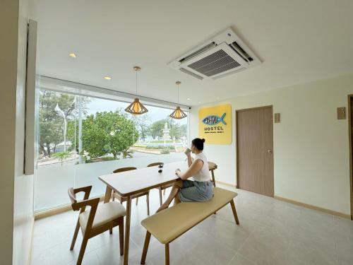 a woman sitting at a table in a room at Fishtail Hostel Phuket in Karon Beach