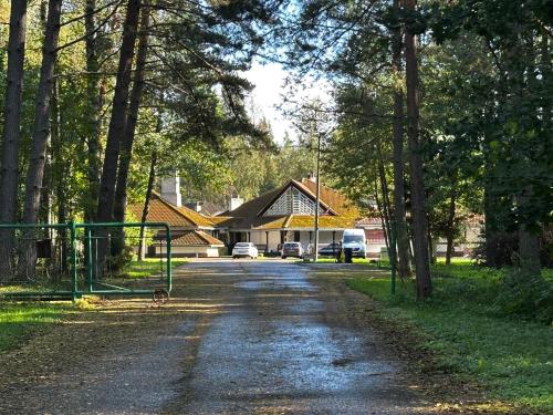a dirt road with trees and a house in the background at Kuivoja Looduskodu in Loksa