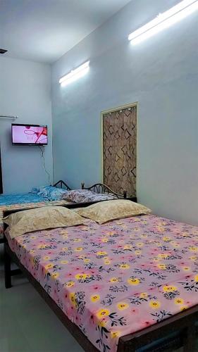 a bedroom with a bed with a floral bedspread at Mamalakandam Green Hill Dormitory in Diya Homesay in Mamalakandam