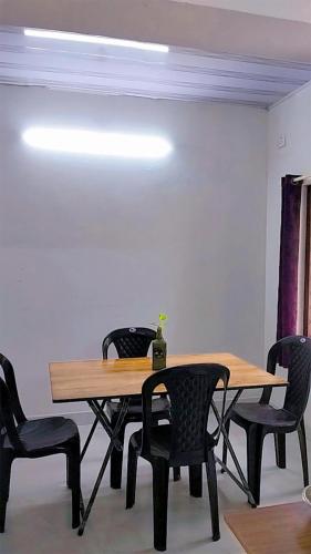 a table with four chairs and a table with a plant on it at Mamalakandam Green Hill Dormitory in Diya Homesay in Mamalakandam