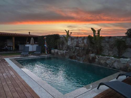 a swimming pool with a sunset in the background at Vivenda pé n'areia in Póvoa de Varzim