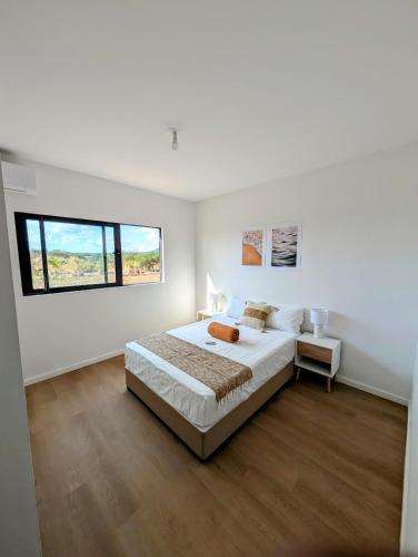 a white bedroom with a large bed and a window at Sea Beach Appartement in Tamarin